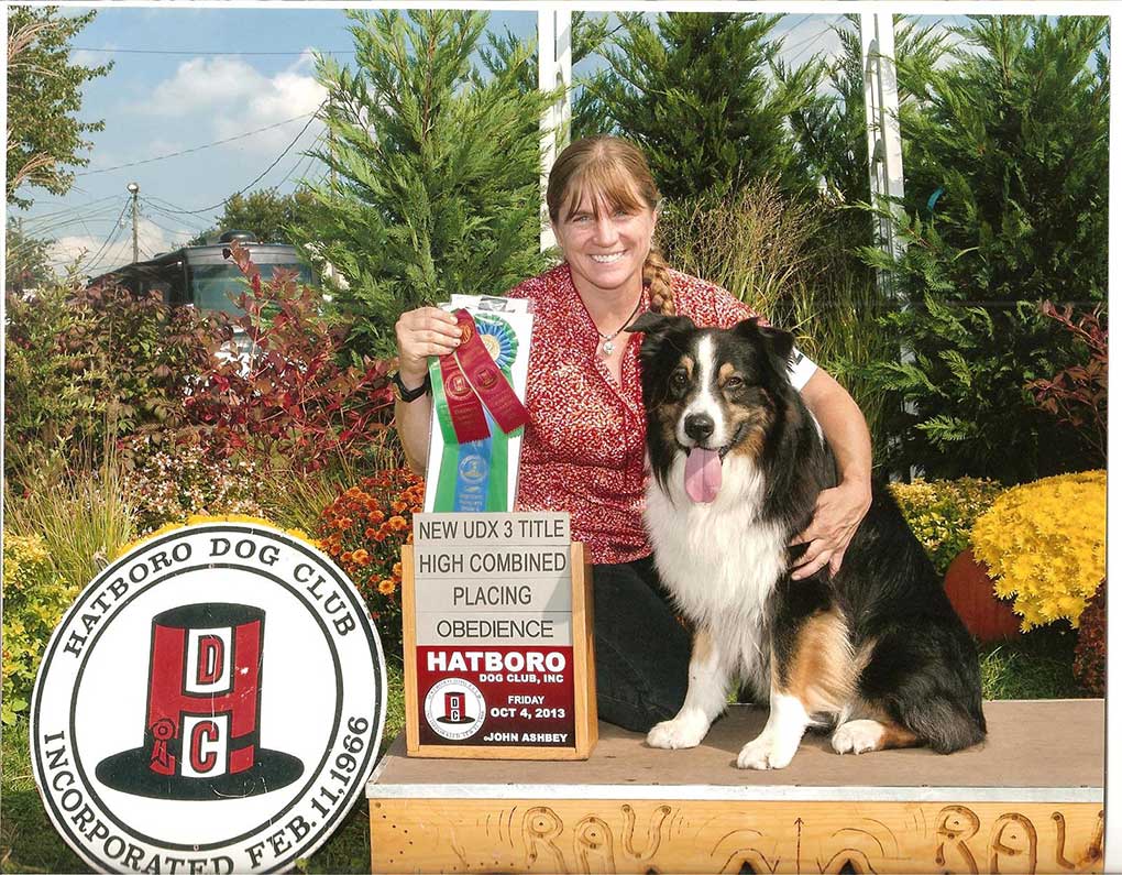 Australian Sheppard sitting with woman holding obedience show ribbons from the Hatboro Dog Club