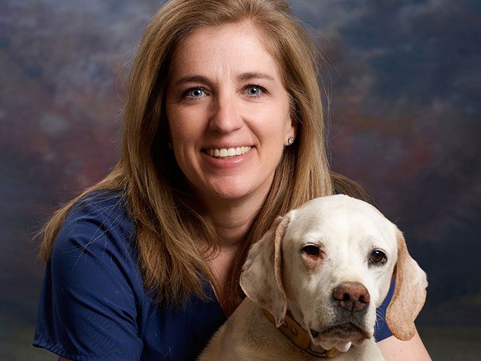 Dr. Carrie Adrian smiling for VCA photo holding Labrador Retriever Mix