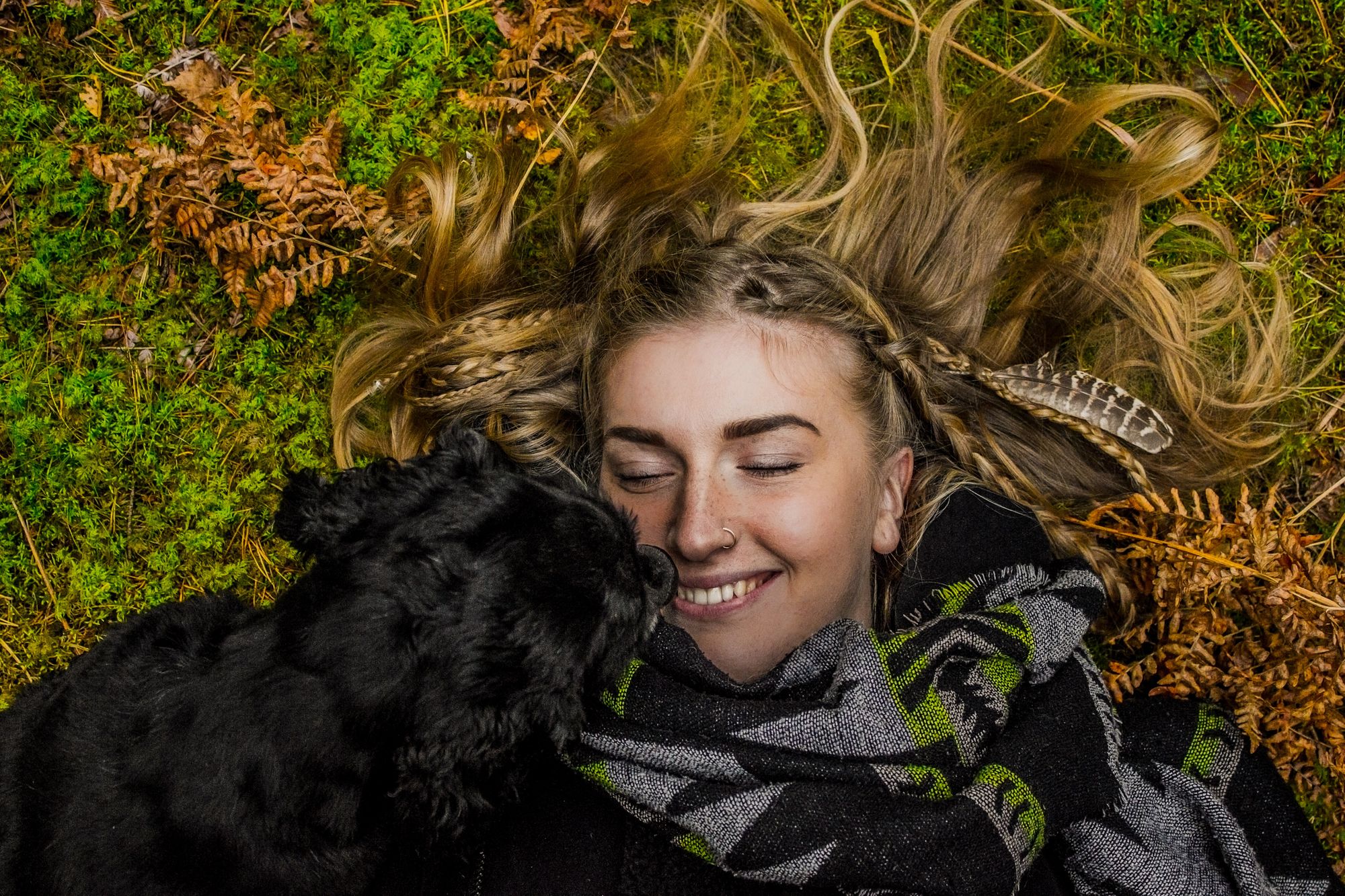 Dog kissing girl lying in the grass